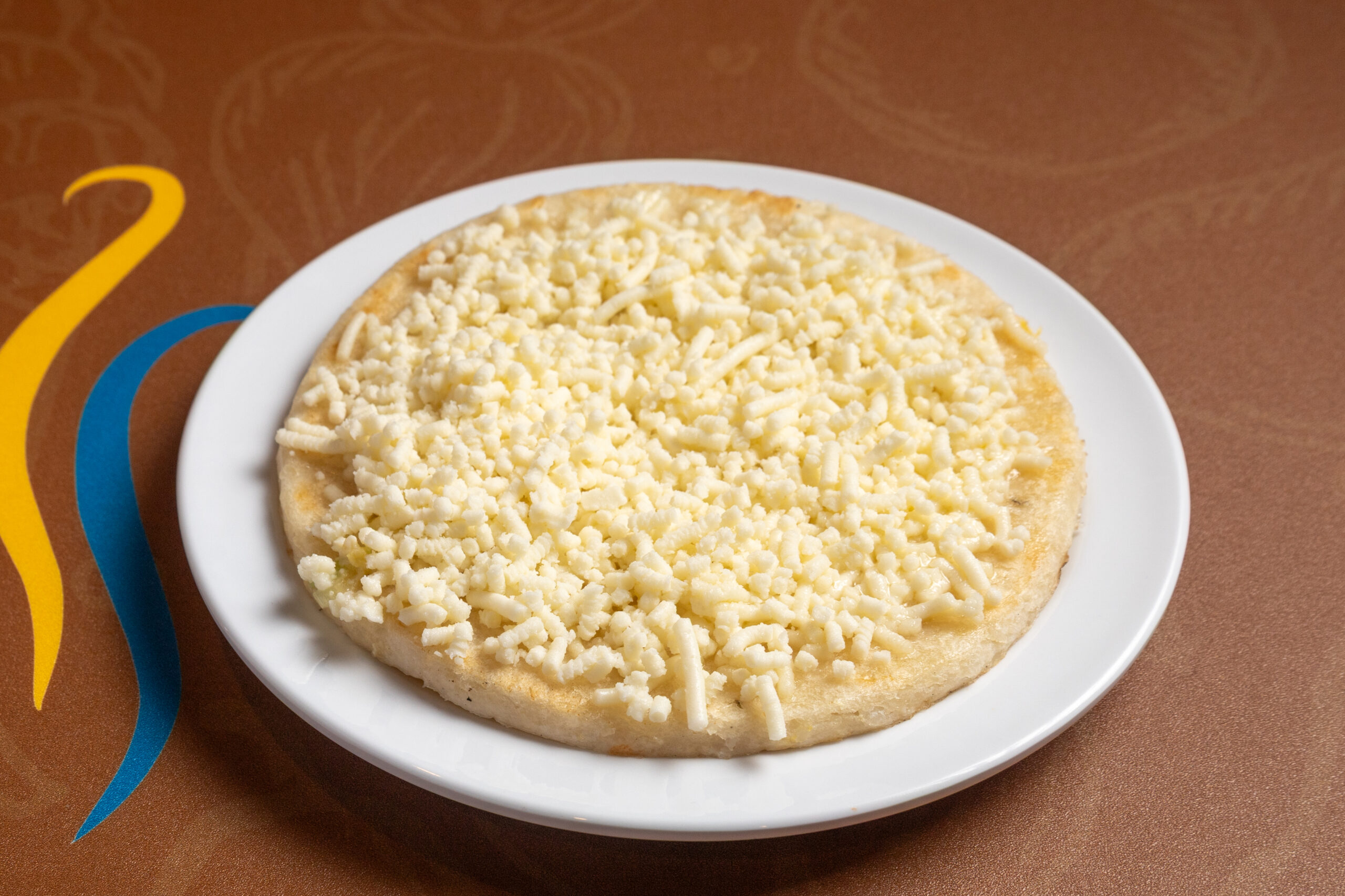 Handcrafted corn griddle arepa topped with melted white cheese at America’s Bakery and Restaurant in Davie, FL.
