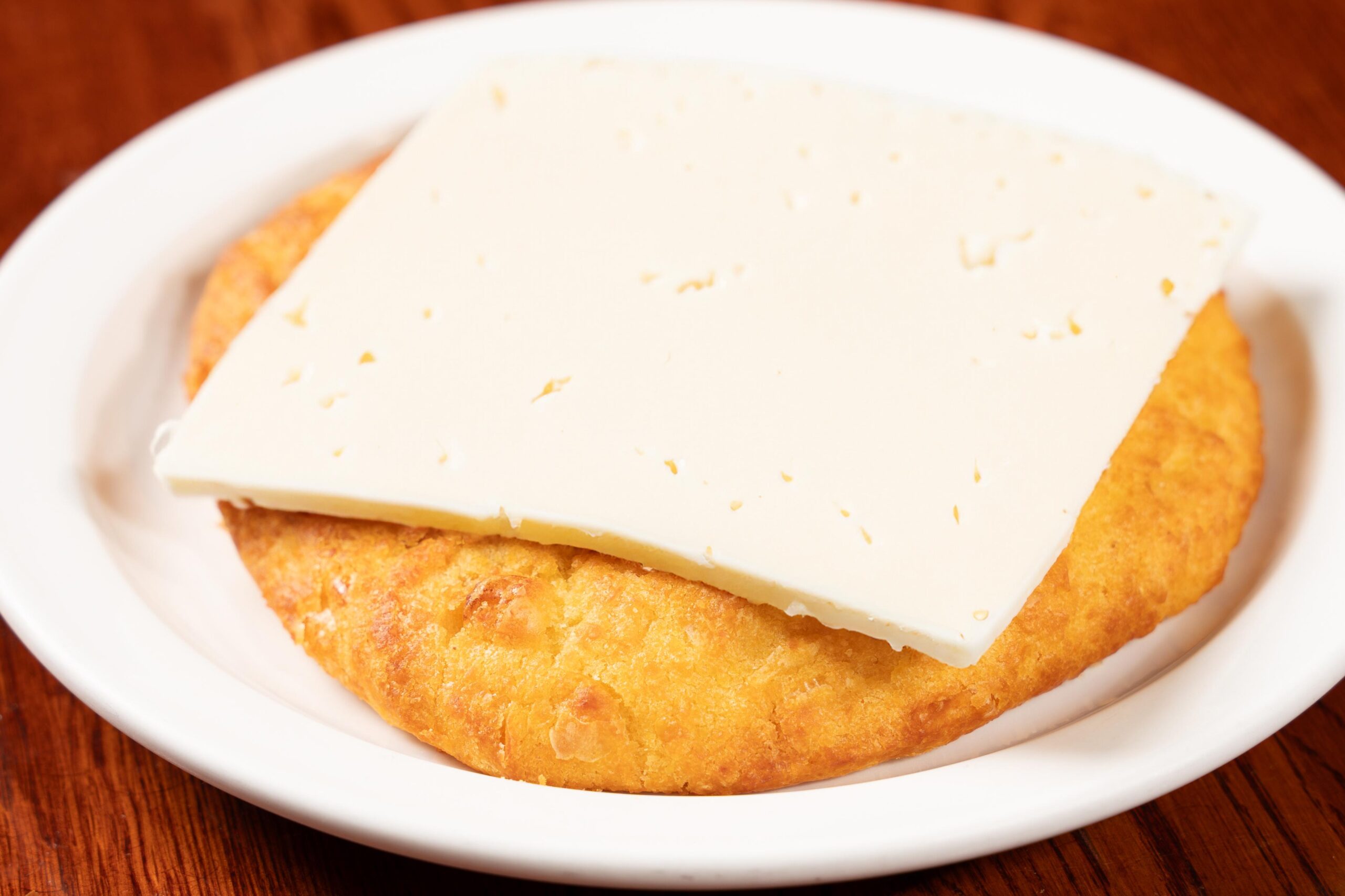 Golden-brown sweet corn arepa de choclo topped with thick melted white cheese at America’s Bakery and Restaurant in Davie, FL.