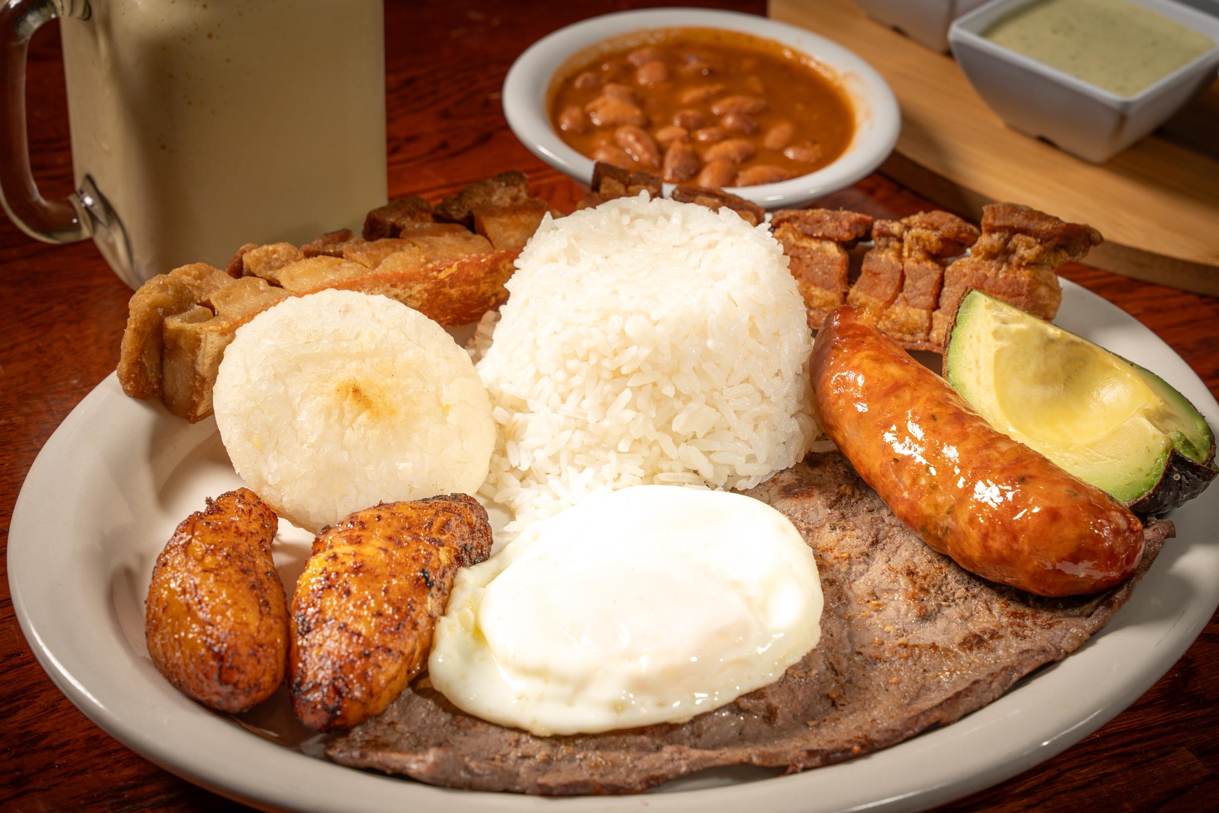 Traditional Colombian Bandeja Paisa with grilled steak, chicharrón, beans, rice, fried egg, and avocado in Davie, FL.