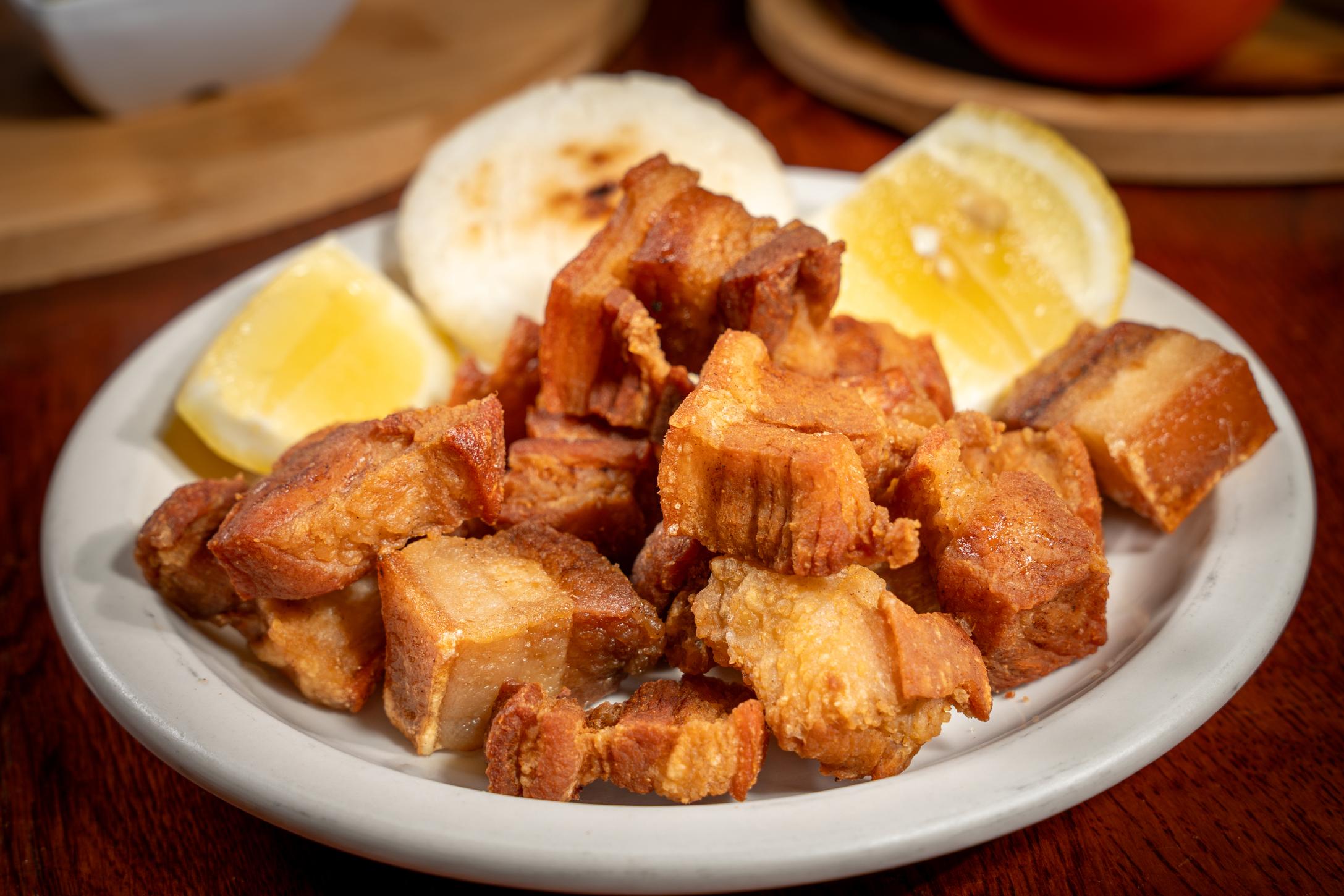 Golden-brown crispy pork belly (chicharrón) served with a traditional small white corn arepa in Davie, FL.