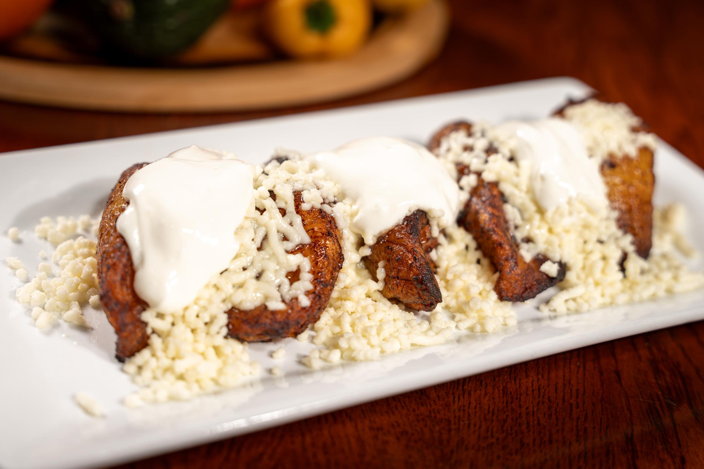 Caramelized sweet yellow plantains topped with white Colombian cheese and crema at America's Bakery in Davie, FL.